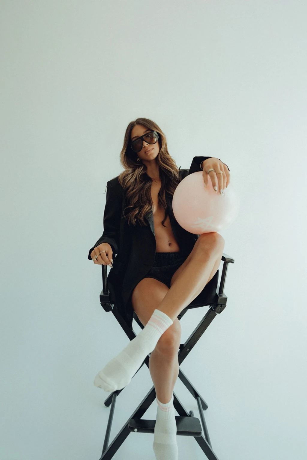 Woman seated in a director chair holding a pale Pilates ball